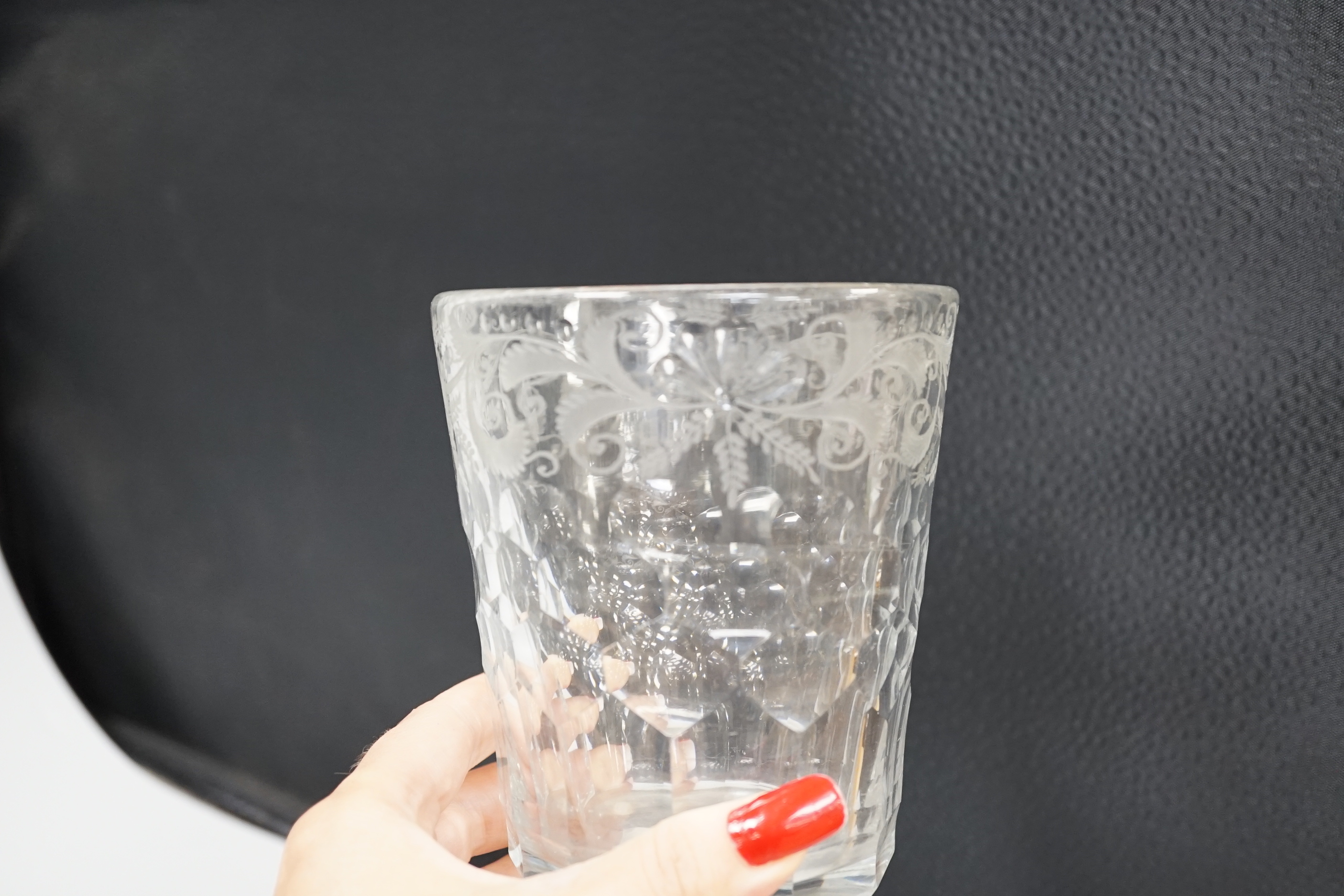 An English lead crystal 18th century faceted tumbler, in a darkish grey metal, upper decoration engraved and polished floral centre, three rows of facets running into plain facets, whole of foot polished to remove pontil